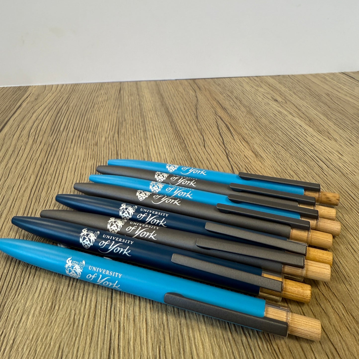 Set of blue and black pens with wooden tips on a wooden surface
