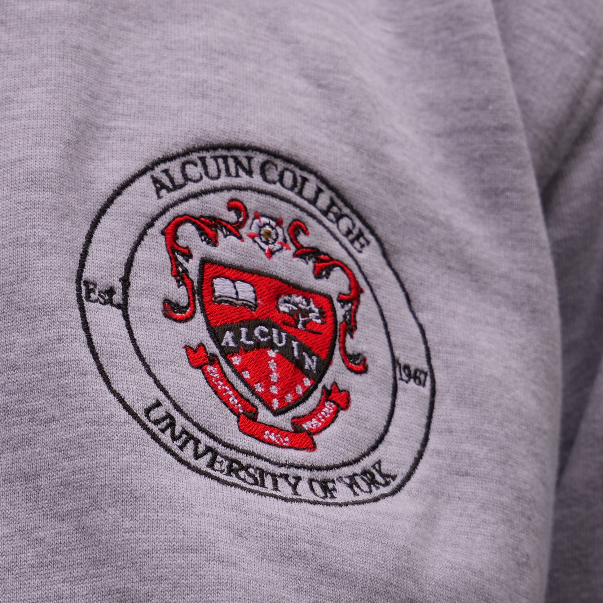 Gray sweatshirt with a red and black emblem and text on the chest.